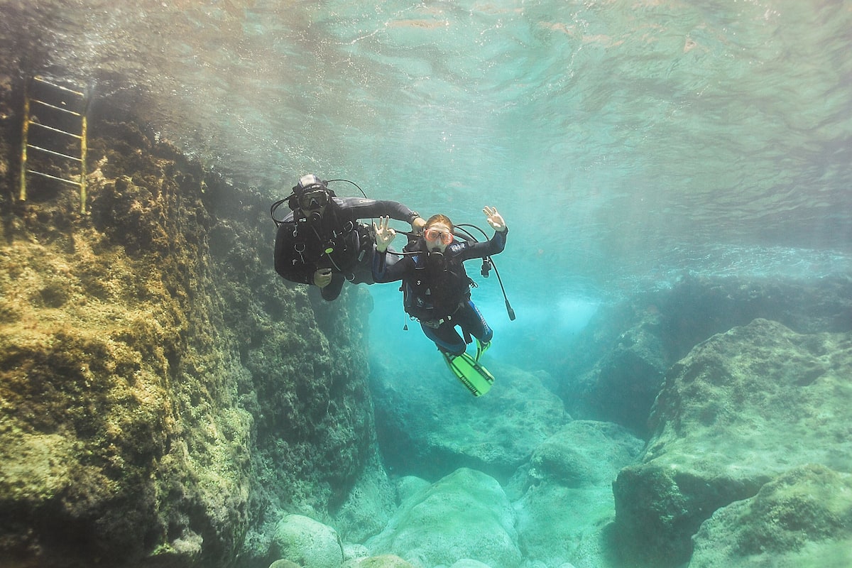 Un plongeur sous l’eau, avec une échelle sur sa gauche.