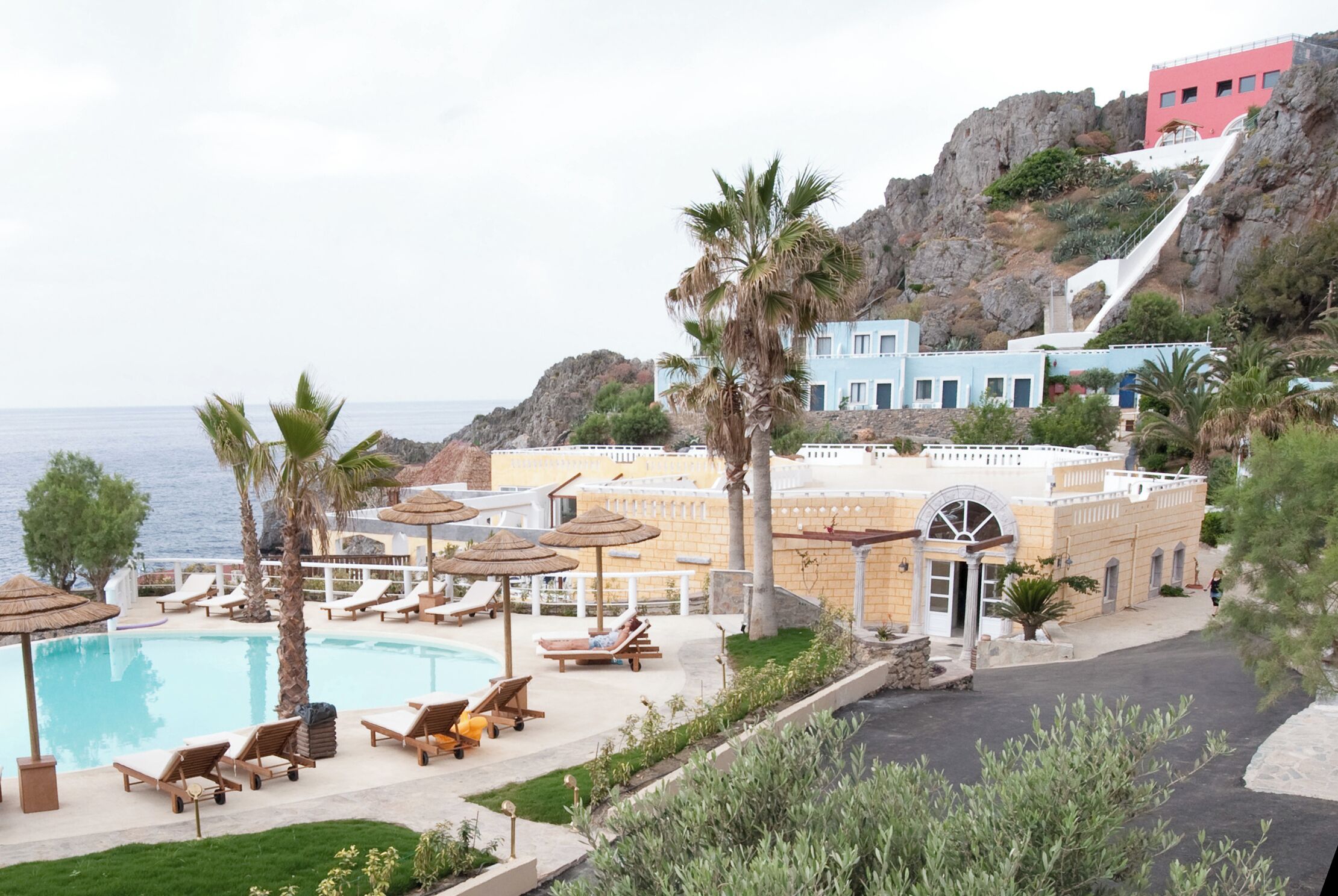 Un resort con piscina, sillones de descanso y vista al mar.