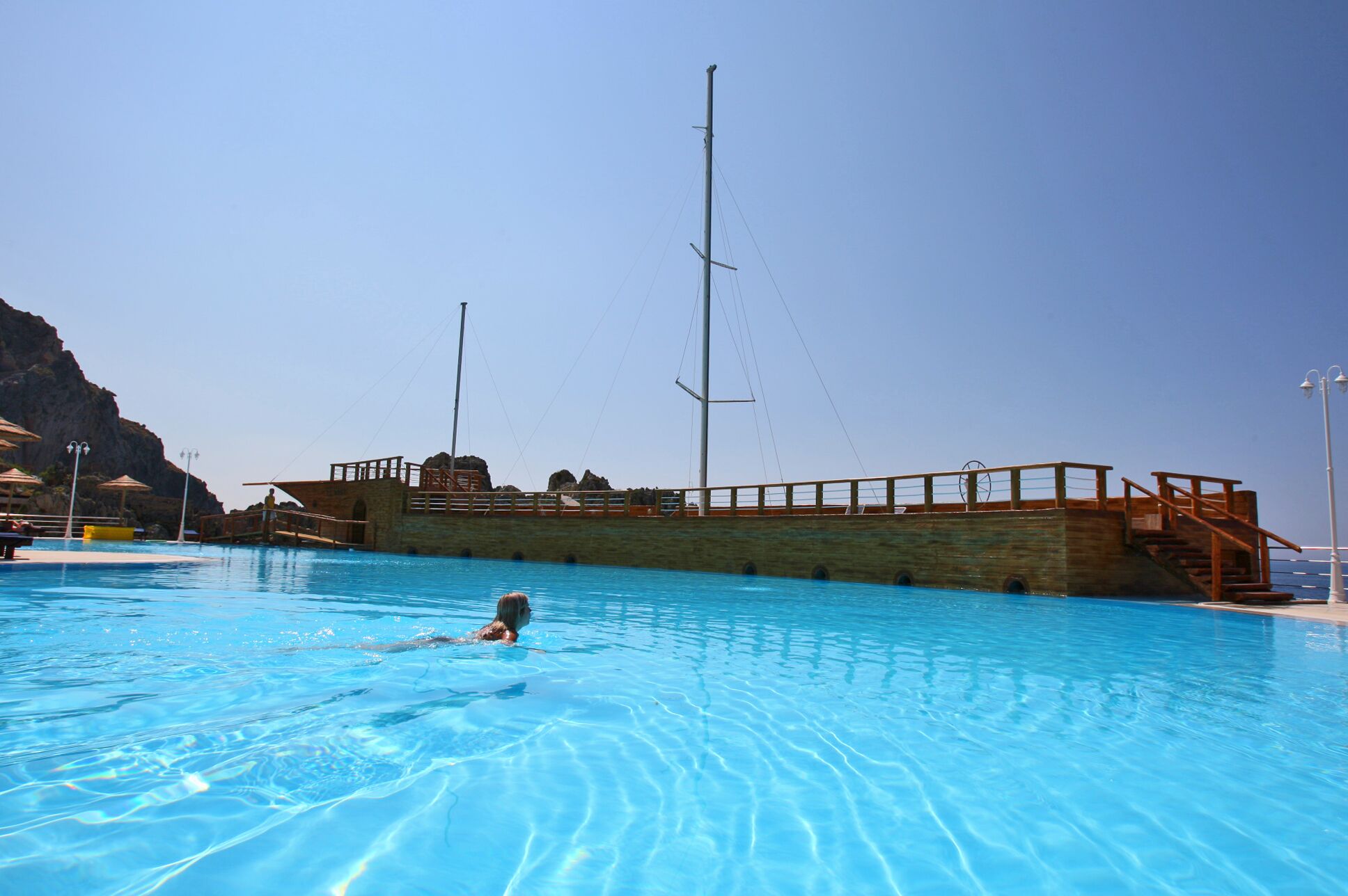 A swimming pool with a wooden deck and a lifeguard tower.