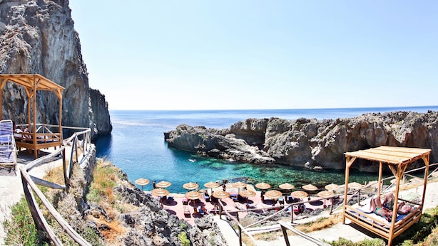 A coastal resort with wooden cabanas, lounge chairs, and umbrellas overlooking the sea.