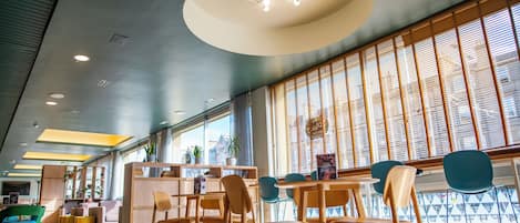 A modern interior with wooden furniture, a central light fixture, and large windows.
