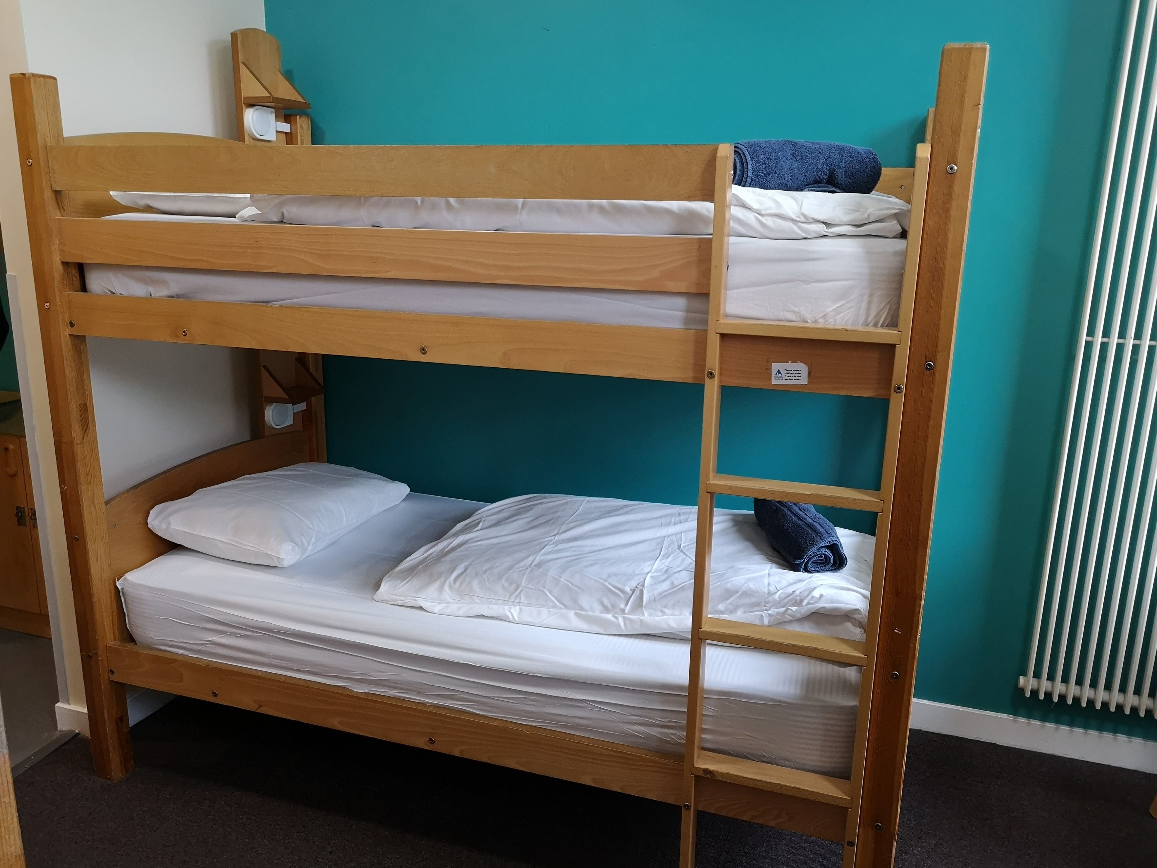 A bunk bed with white bedding and a blue towel.