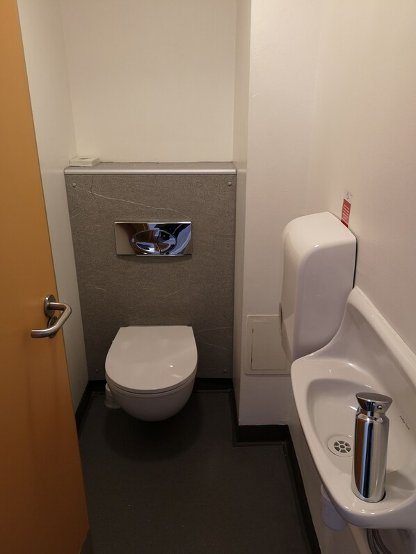 A small, compact bathroom with a toilet, urinal, and a paper towel dispenser. - Edinburgh Central Youth Hostel (Edinburgh)
