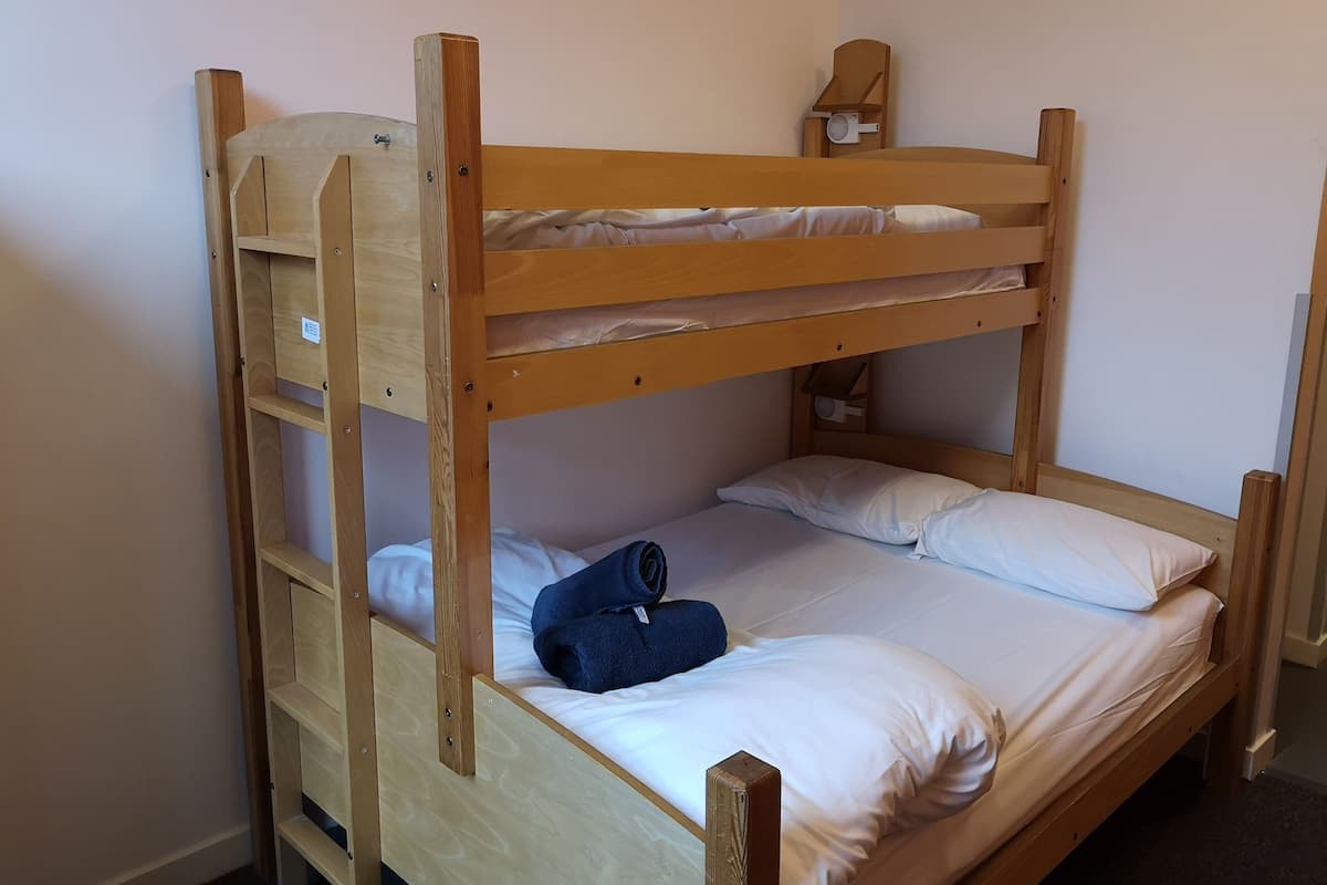 A bunk bed with a wooden frame, a small shelf, and a night light.