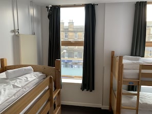 A room with two wooden bunk beds, a radiator, and a window with curtains. - Edinburgh Central Youth Hostel (Edinburgh)