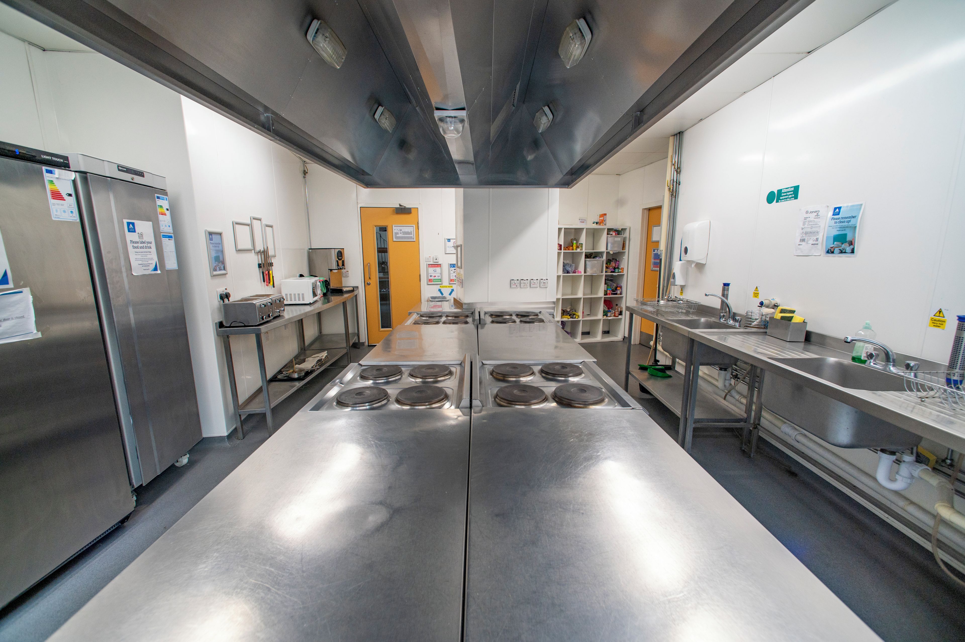 A commercial kitchen with stainless steel appliances, a central island, and a sink area.