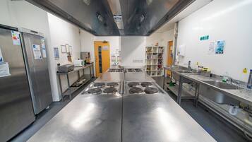 A commercial kitchen with stainless steel appliances, a central island, and a sink area.