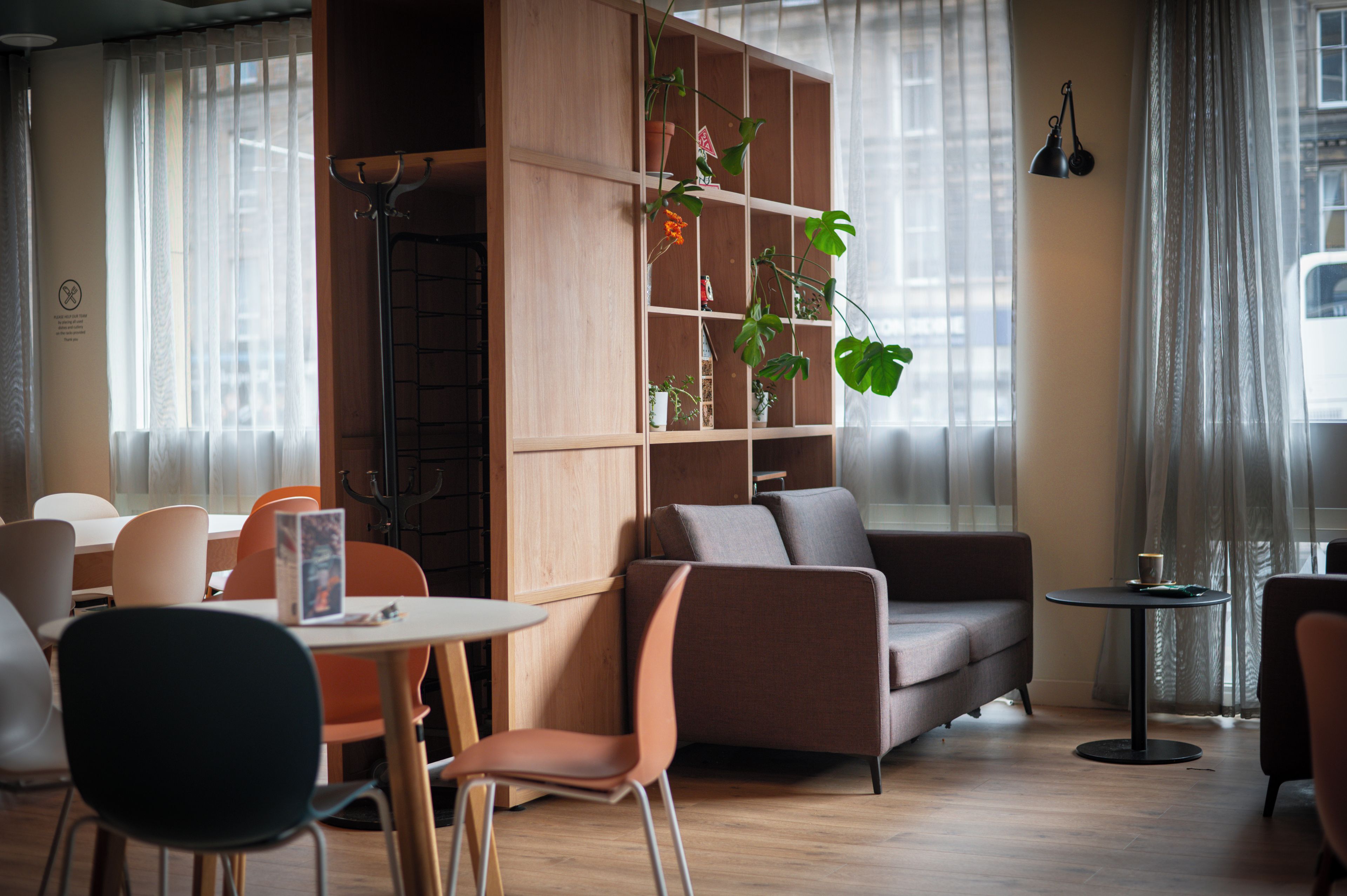 A modern interior with a sofa, chairs, a table, and a bookshelf with plants.