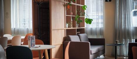 A modern interior with a sofa, chairs, a table, and a bookshelf with plants.