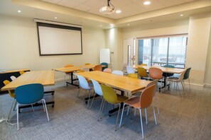 A conference room with multiple tables and chairs, a projector screen, and a whiteboard. - Edinburgh Central Youth Hostel (Edinburgh)