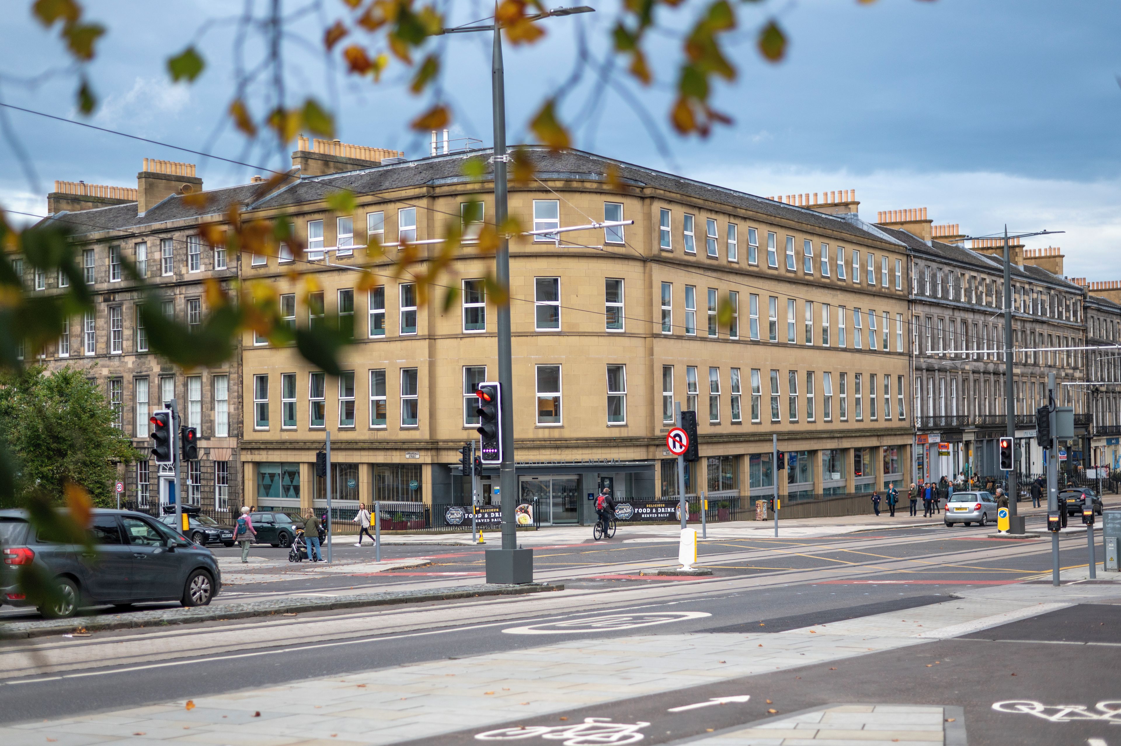 A multi-story building with a corner entrance, a pedestrian crossing, and a bicycle lane.