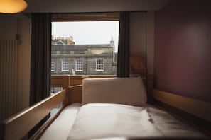 A hotel room with a bed, a window, and a view of a building outside. - Edinburgh Central Youth Hostel (Edinburgh)