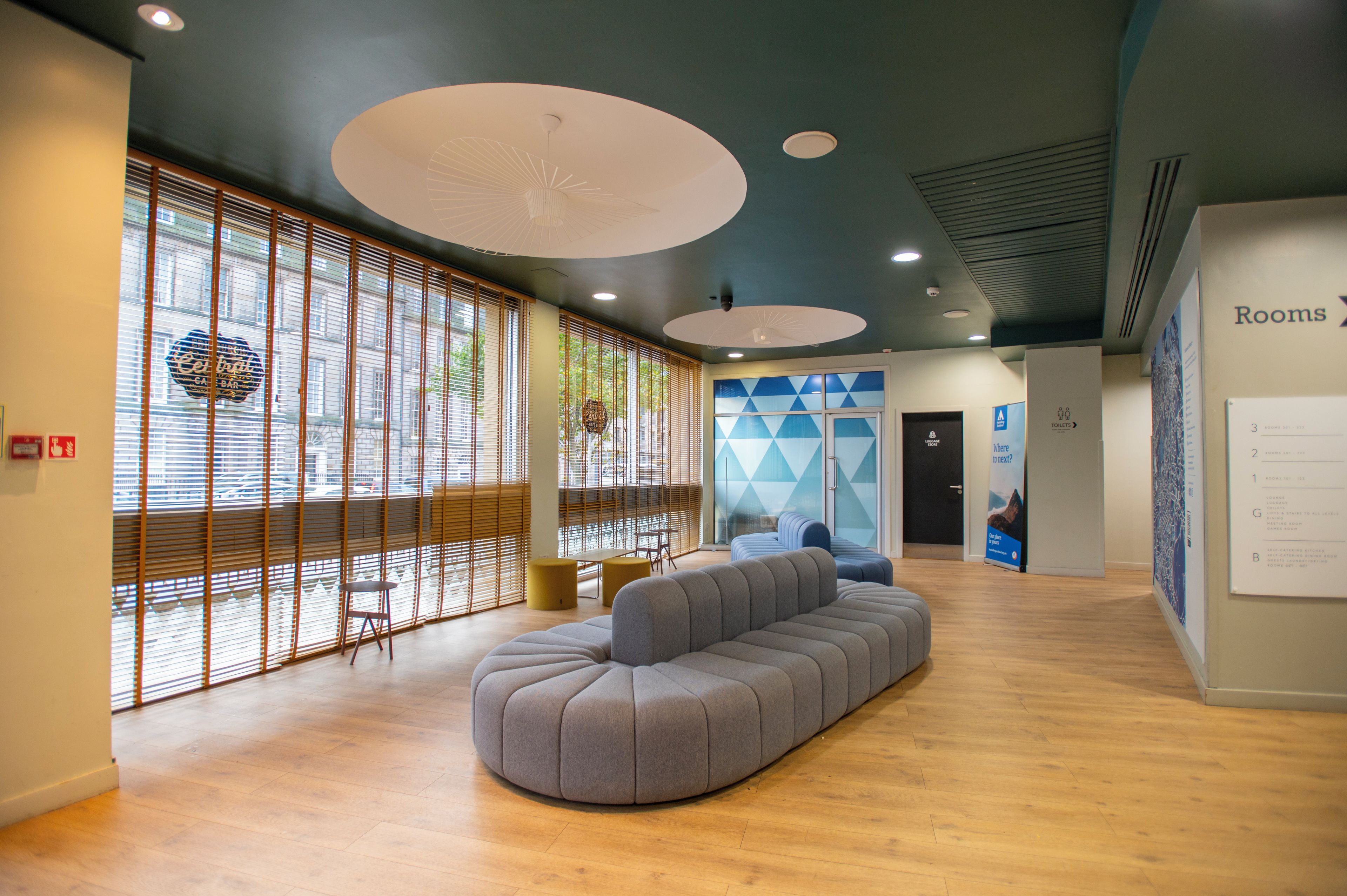 Een moderne lobby met een zithoek, een receptiebalie en een bord met de kamerindeling.