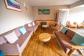 Ein Zimmer mit Kamin, karierten Sofas, einem runden Holztisch und einem Gemälde an der Wand.