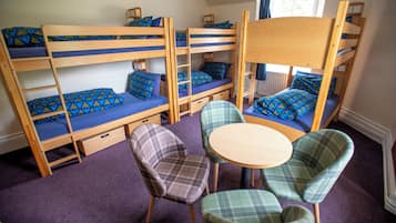 A bunk bed room with a small table and two chairs.