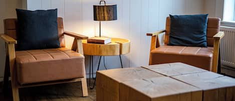 A room with two leather armchairs, a wooden coffee table, and a small side table with a lamp.