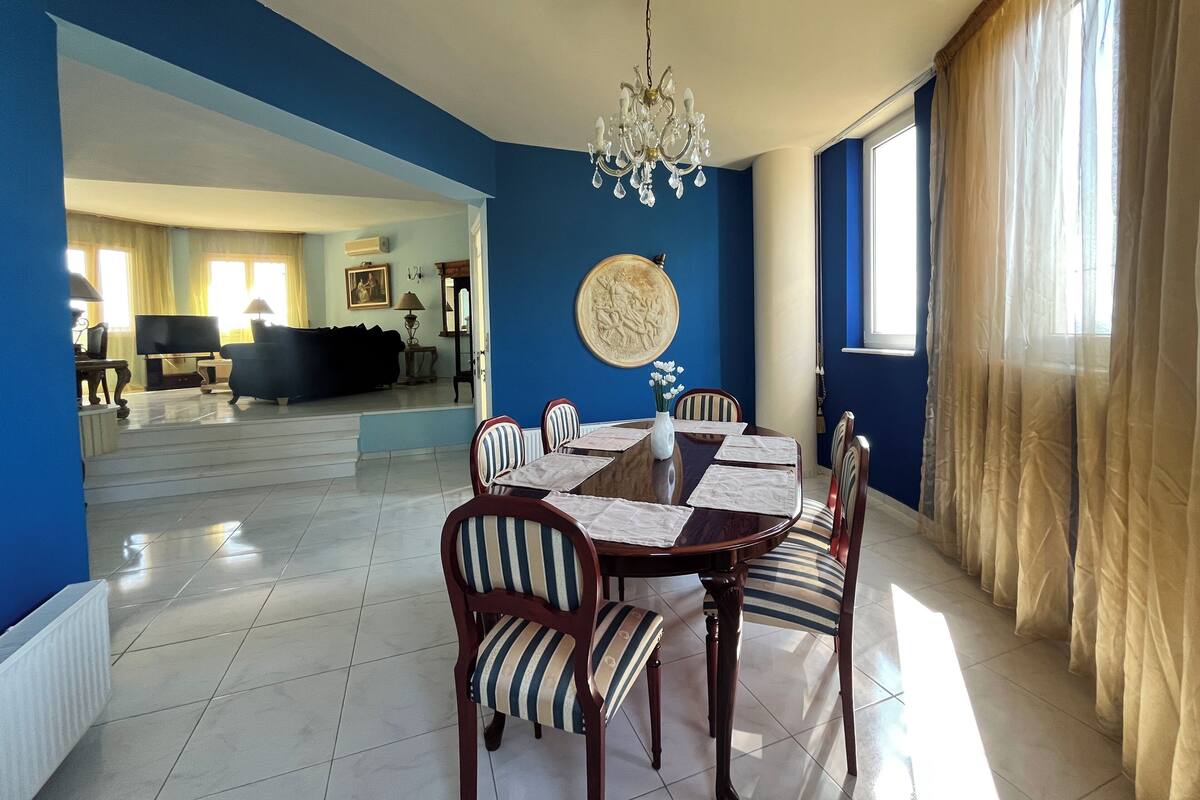 A dining area with a chandelier, a round table, and striped chairs.