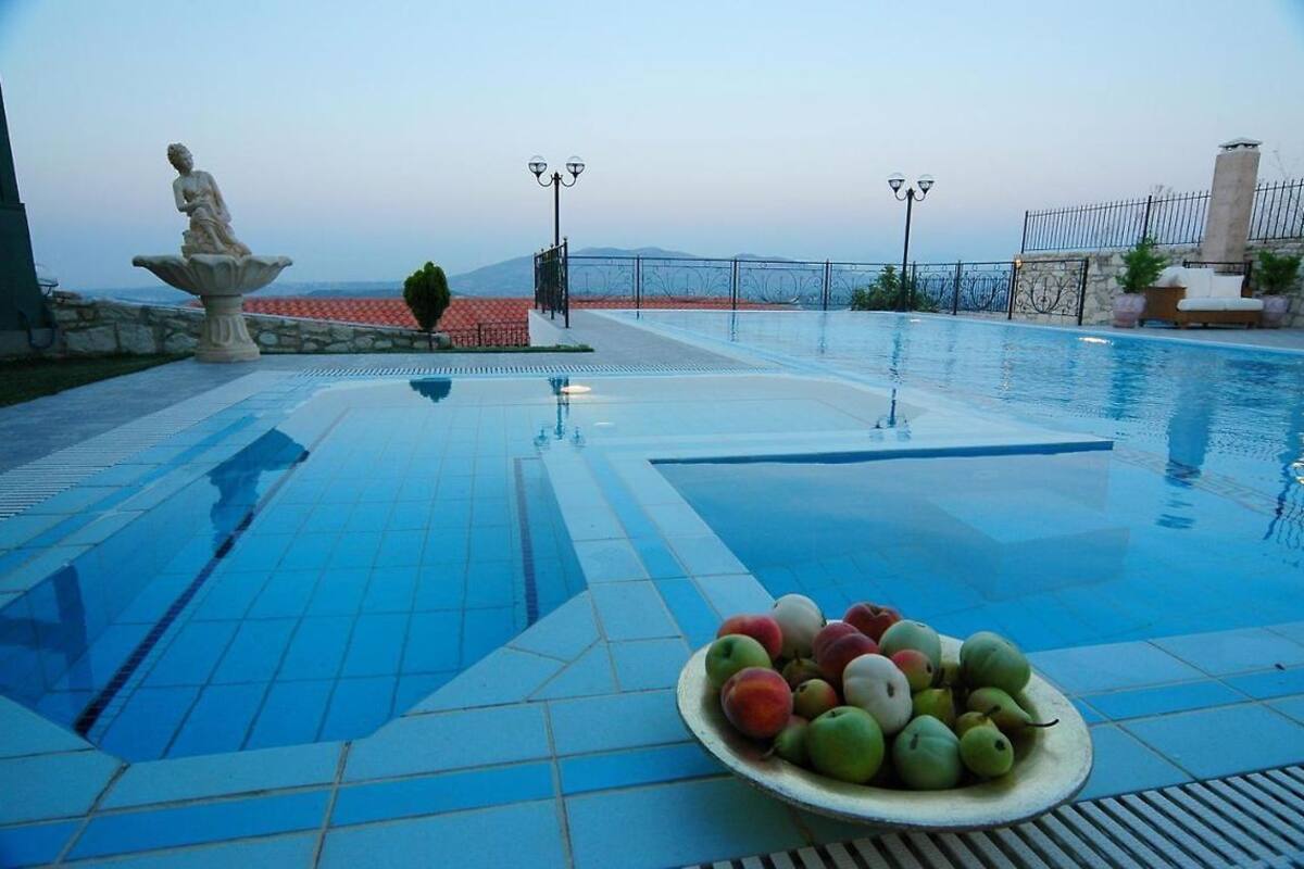 A swimming pool with a statue, a fruit bowl, and a view of the sea.