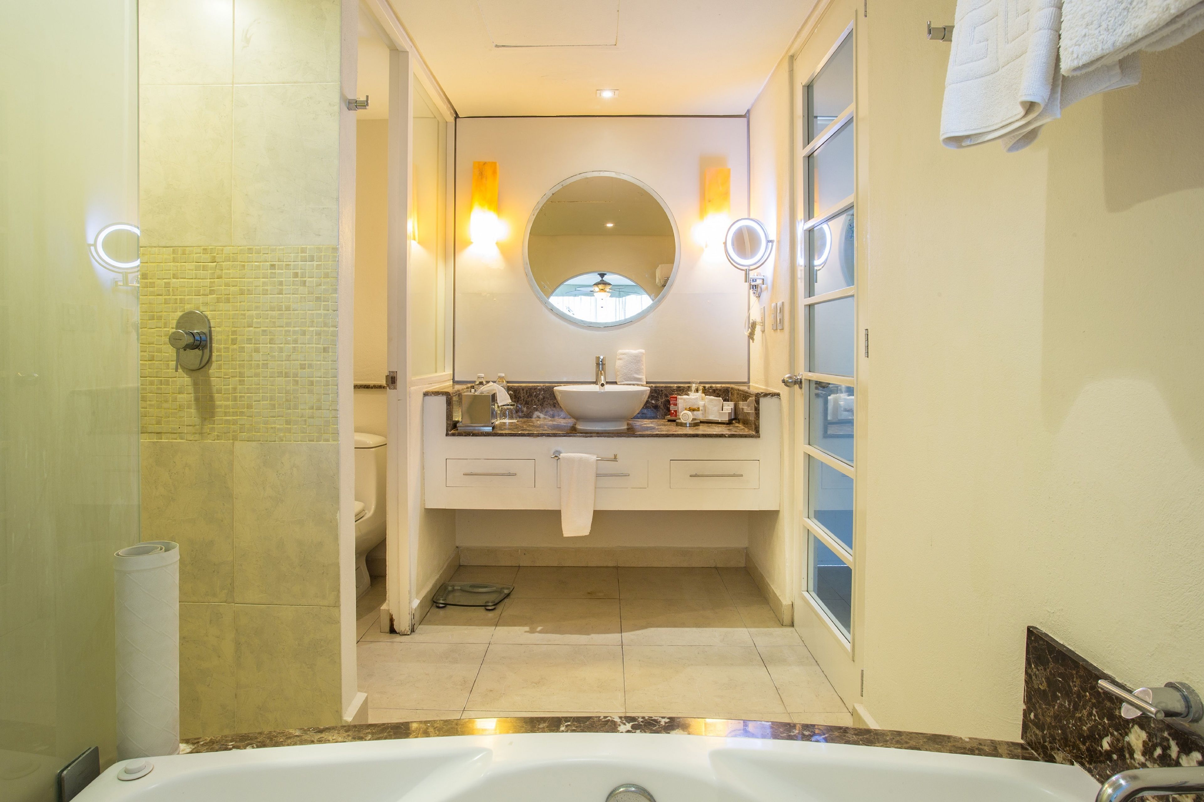 A modern bathroom with a large bathtub, a round mirror, and a vanity with a sink and countertop.