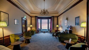 A spacious lobby with a high ceiling, elegant chandeliers, and a view through large windows.