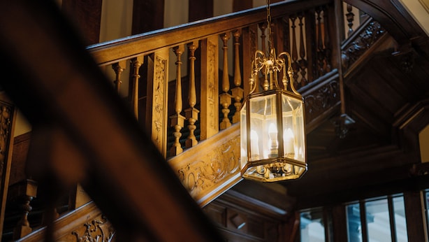 A wooden staircase with ornate railings and a hanging lantern.