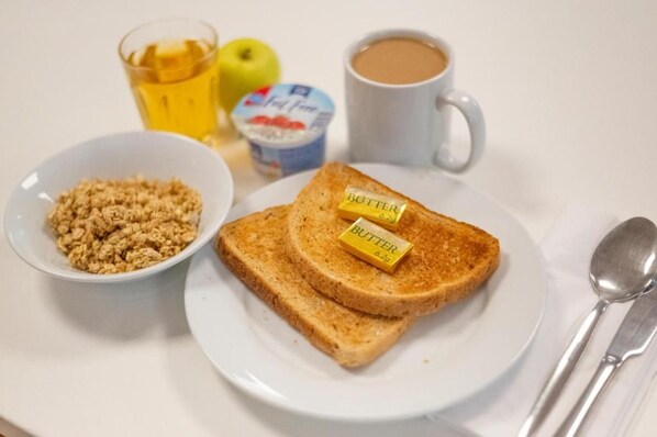 Un plato de desayuno con tostadas, mantequilla y un tazón de cereales.