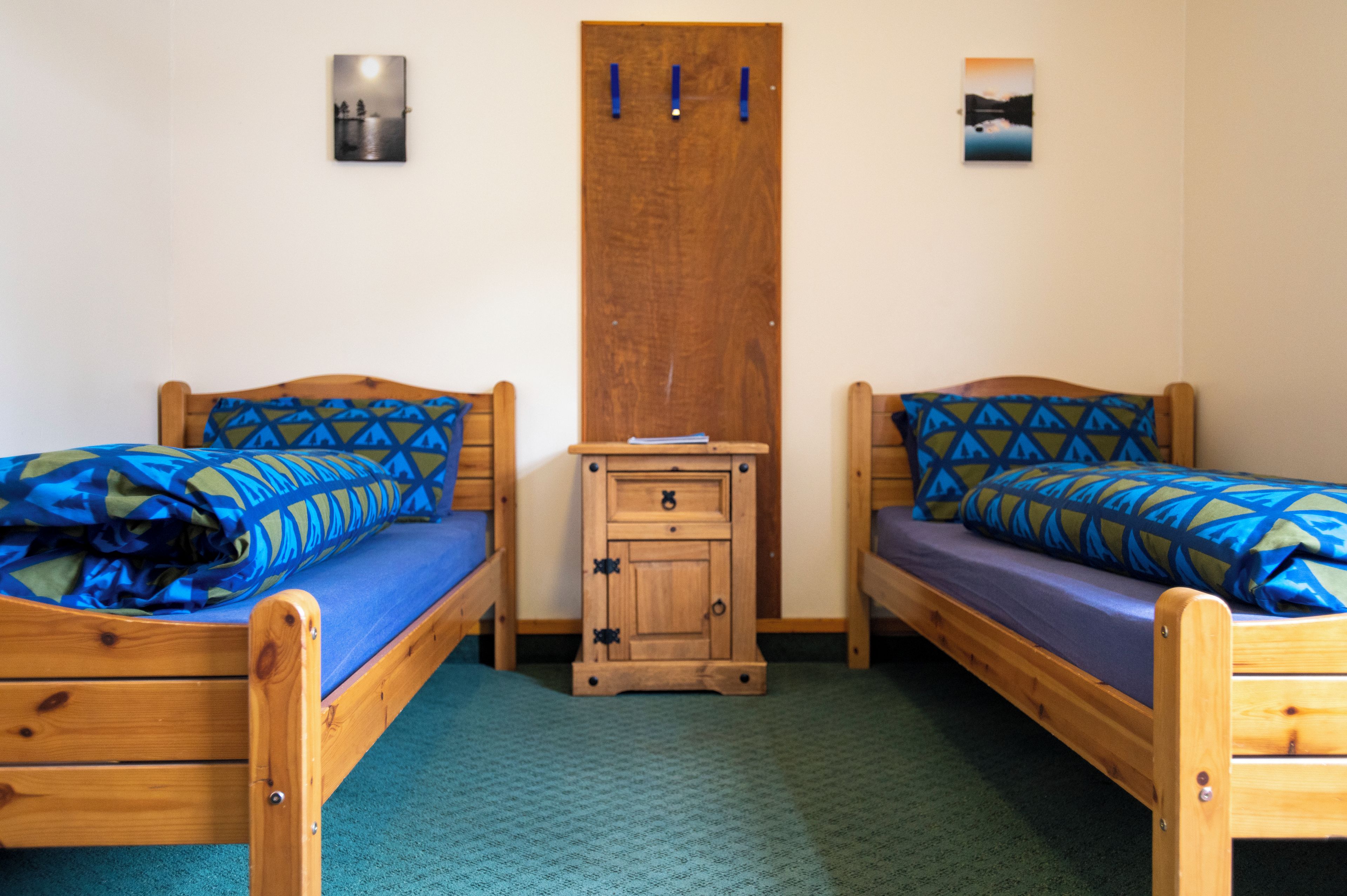 Habitació amb dos llits de fusta, cadascun amb roba de llit de disseny blau.