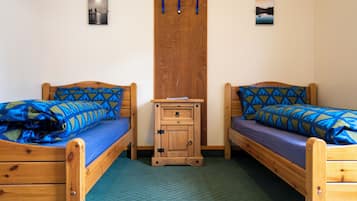 Habitació amb dos llits de fusta, cadascun amb roba de llit de disseny blau.