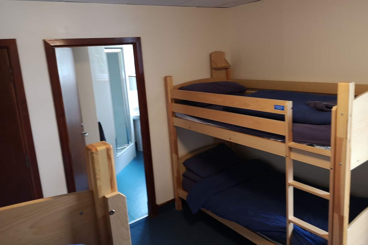 A bunk bed room with a wooden frame, a door, and a window.