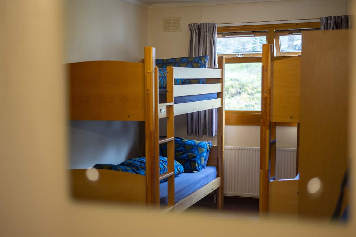 A bunk bed room with a window and curtains.