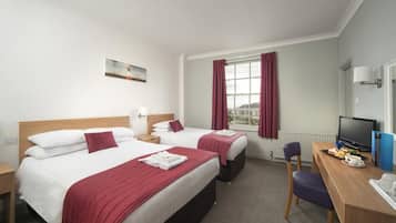 A hotel room with two beds, a desk with a computer, a chair, and a window with curtains.