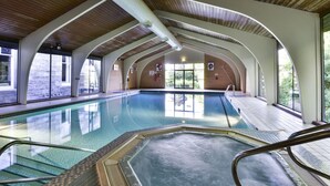 An indoor swimming pool with clear glass walls, a wooden ceiling, and a view of the outside. - The Pitlochry Hydro Hotel (Pitlochry)