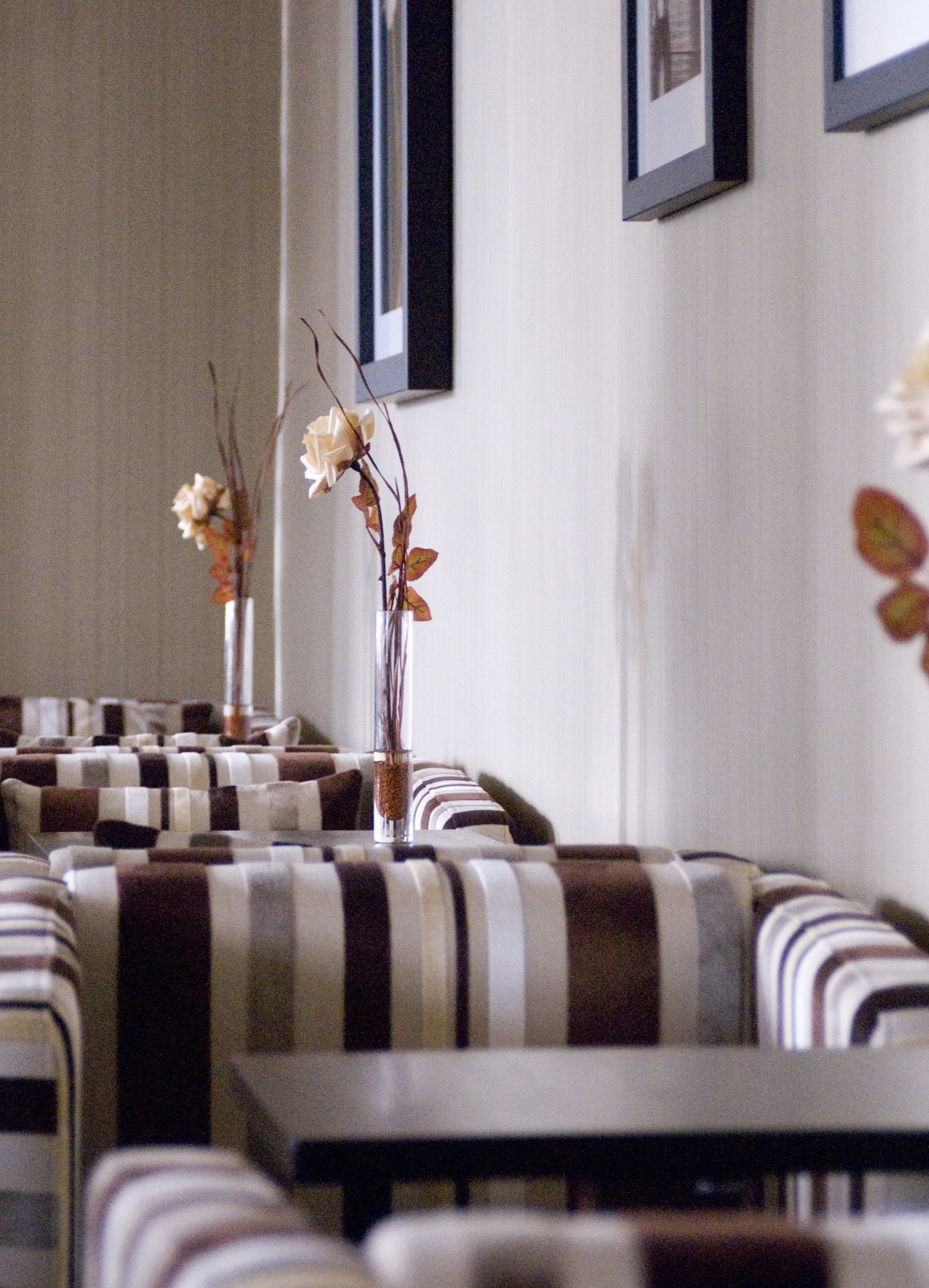 A seating area with striped cushions and a vase with flowers.