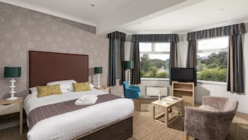 Habitación de hotel con una cama grande, televisor, escritorio y una silla.