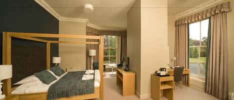 A bedroom with a four-poster bed, a desk, a chair, and a television.