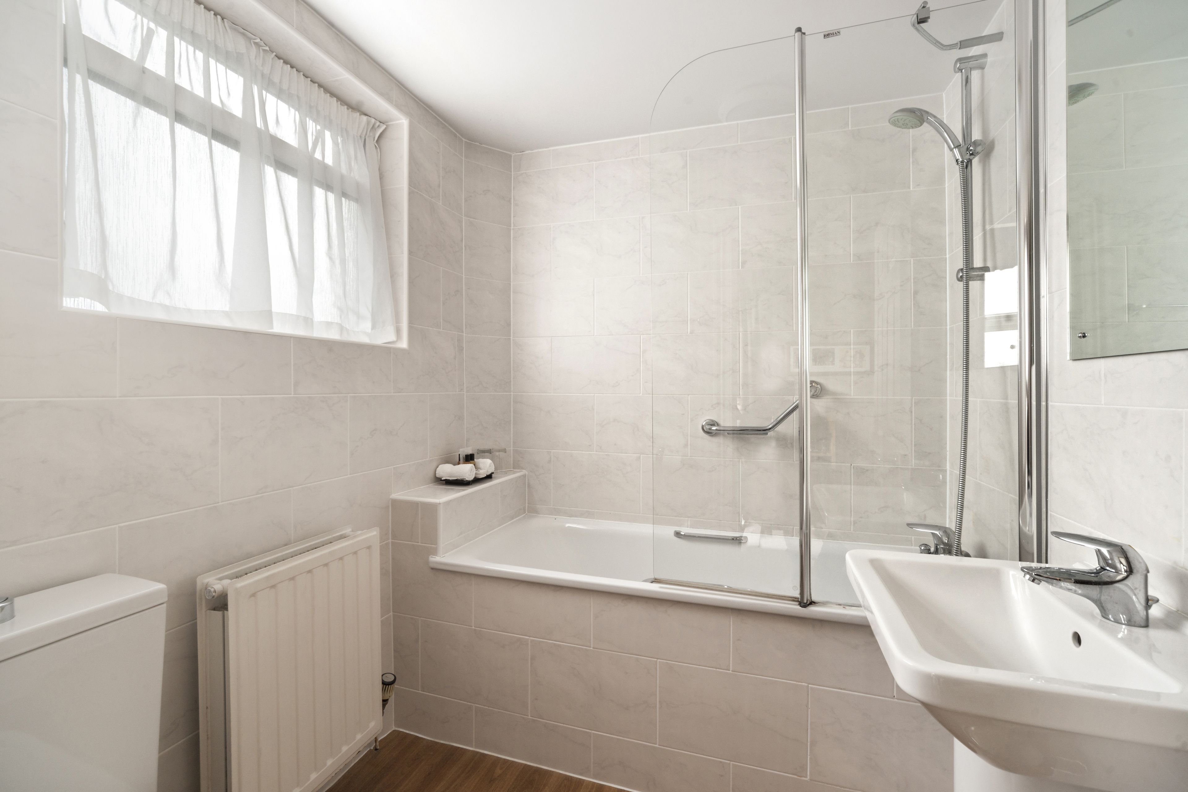 A modern bathroom with a glass-enclosed shower, a standalone bathtub, and a pedestal sink.