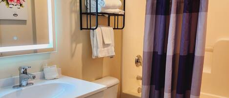 A bathroom with a white sink, a toilet, a mirror, and a shower curtain.