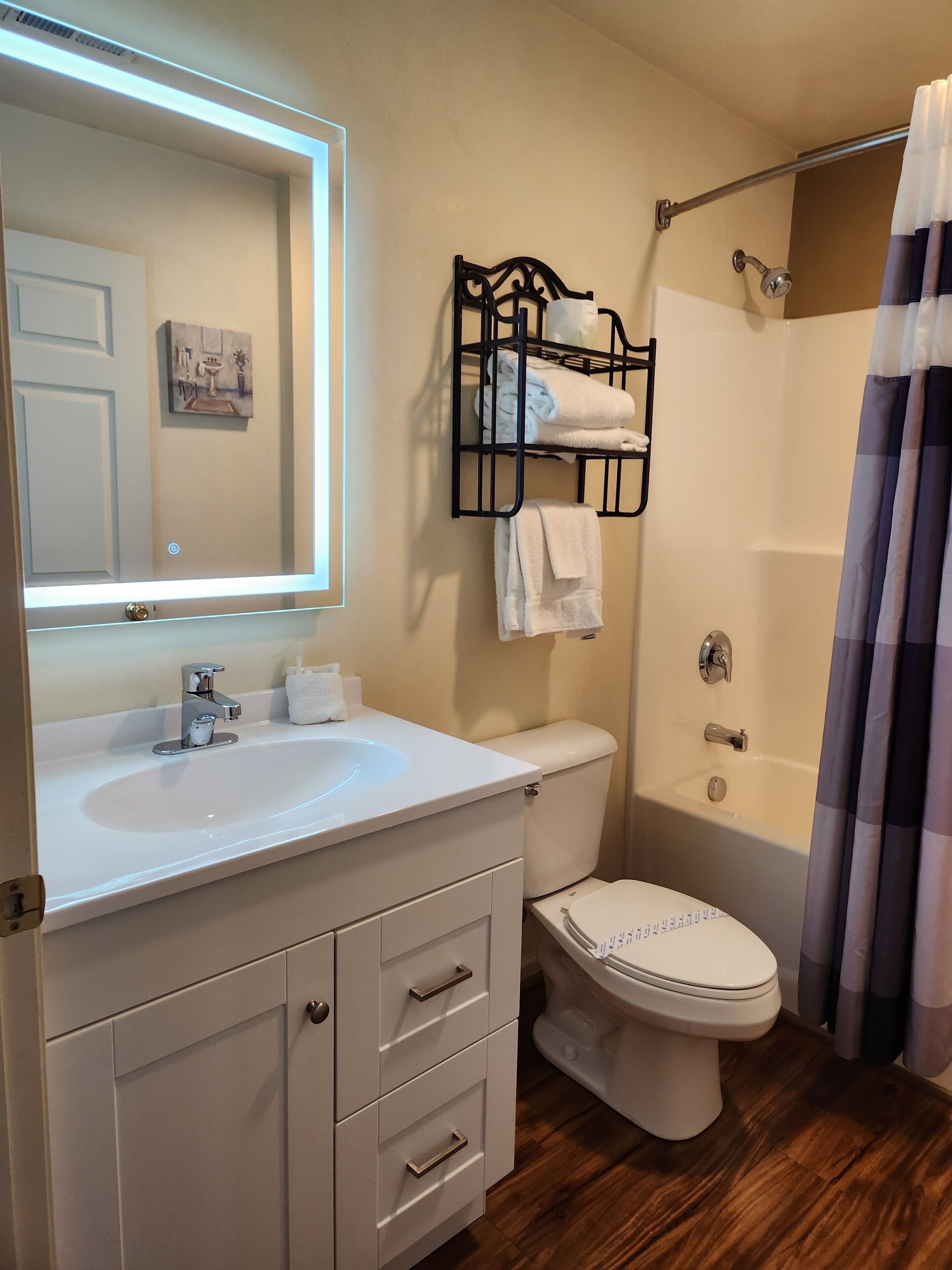 A bathroom with a white sink, a toilet, a shower with a curtain, and a towel rack.