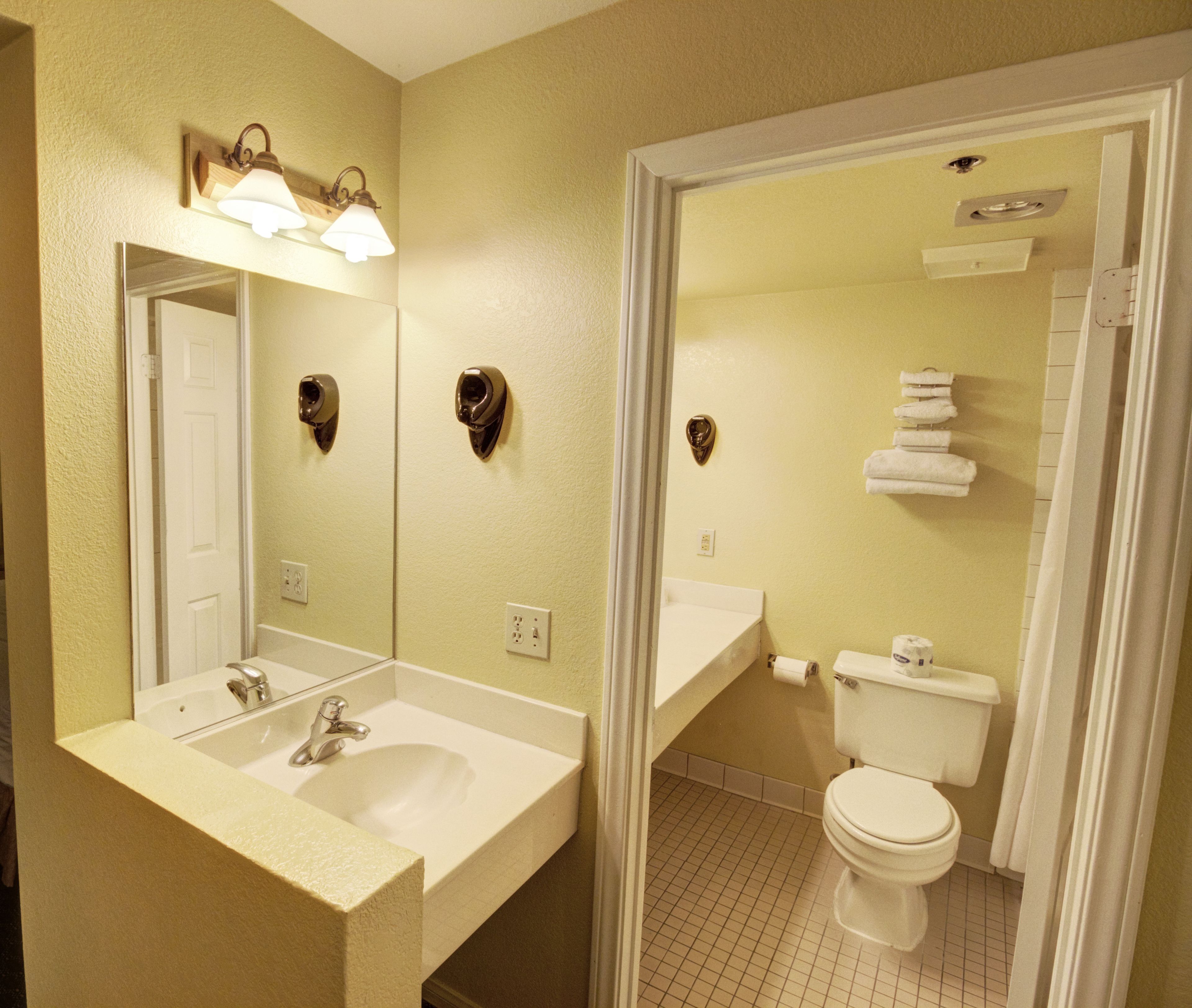 A bathroom with a sink, mirror, toilet, and towel rack.