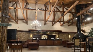 A spacious lobby with a stone floor, wooden beams, leather seating, a reception desk, and a fireplace.