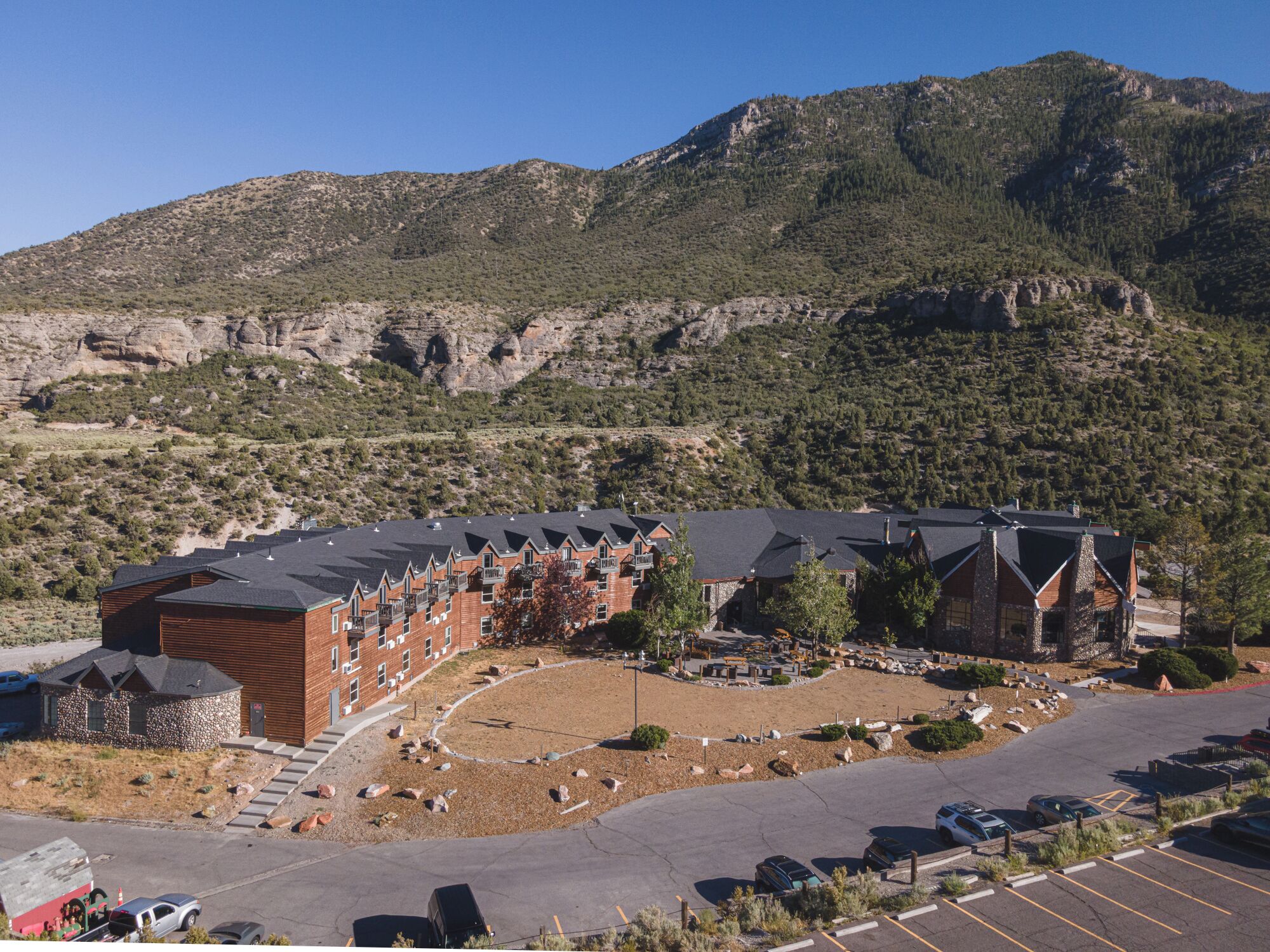 A hotel with multiple buildings, a parking lot, and a mountainous backdrop.