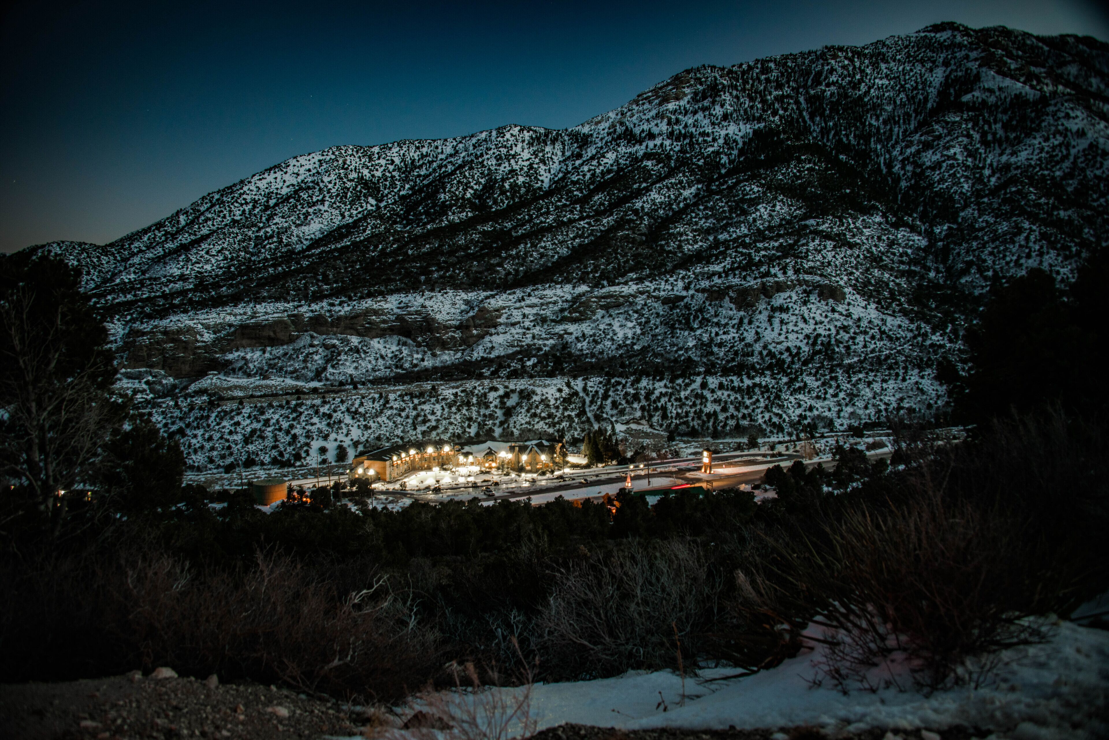 A snow-covered mountain with a lit building in the foreground.
