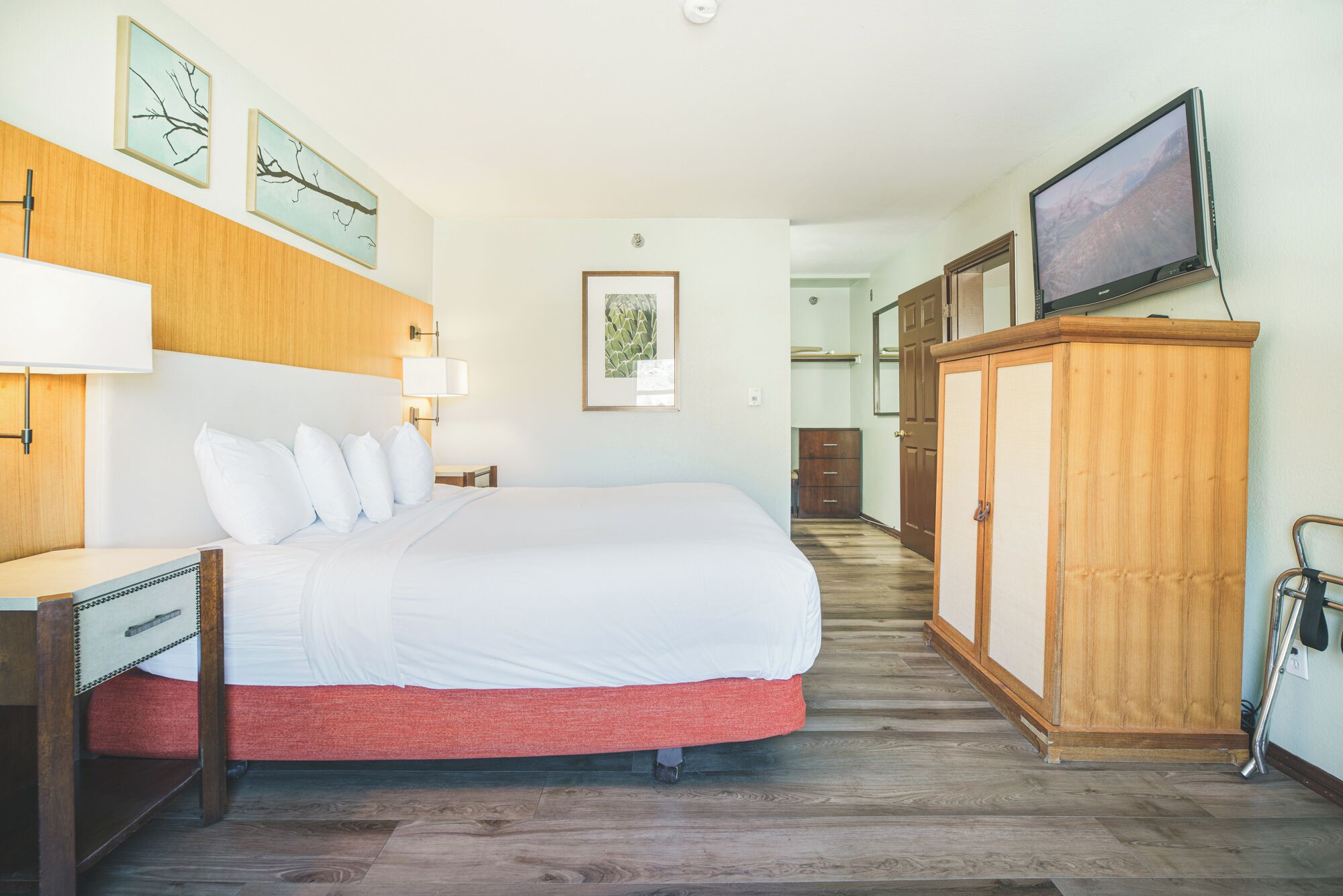 Una habitación de hotel con cama, escritorio, armario y televisor.
