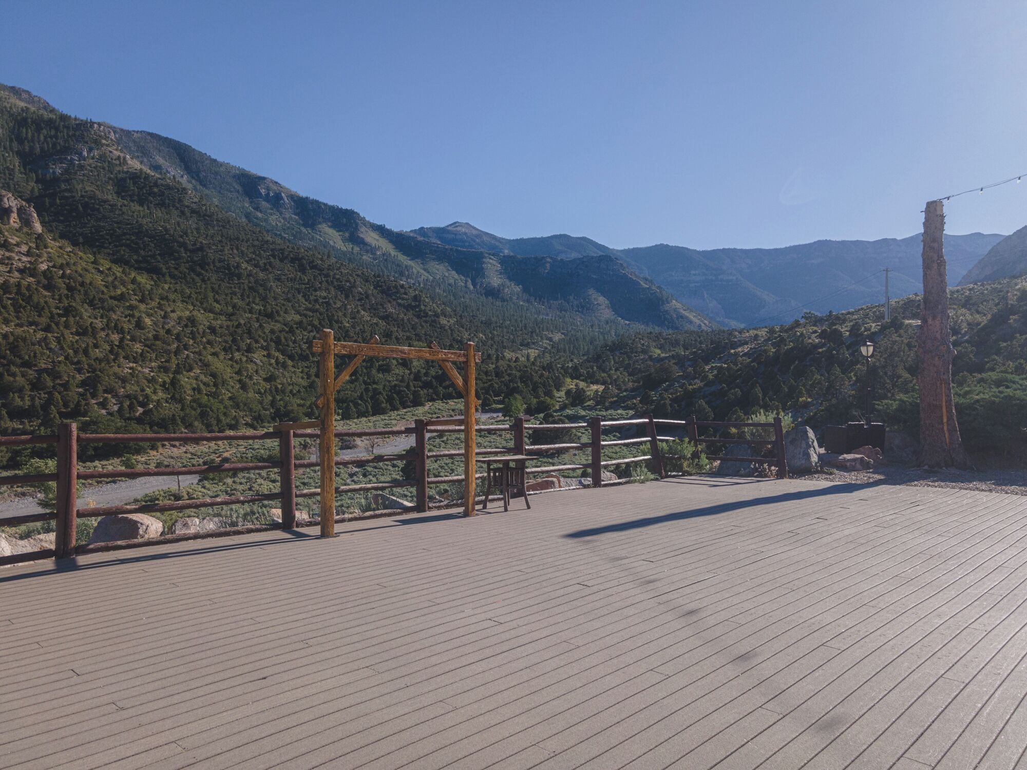 A wooden deck with a metal railing overlooking a mountainous landscape.