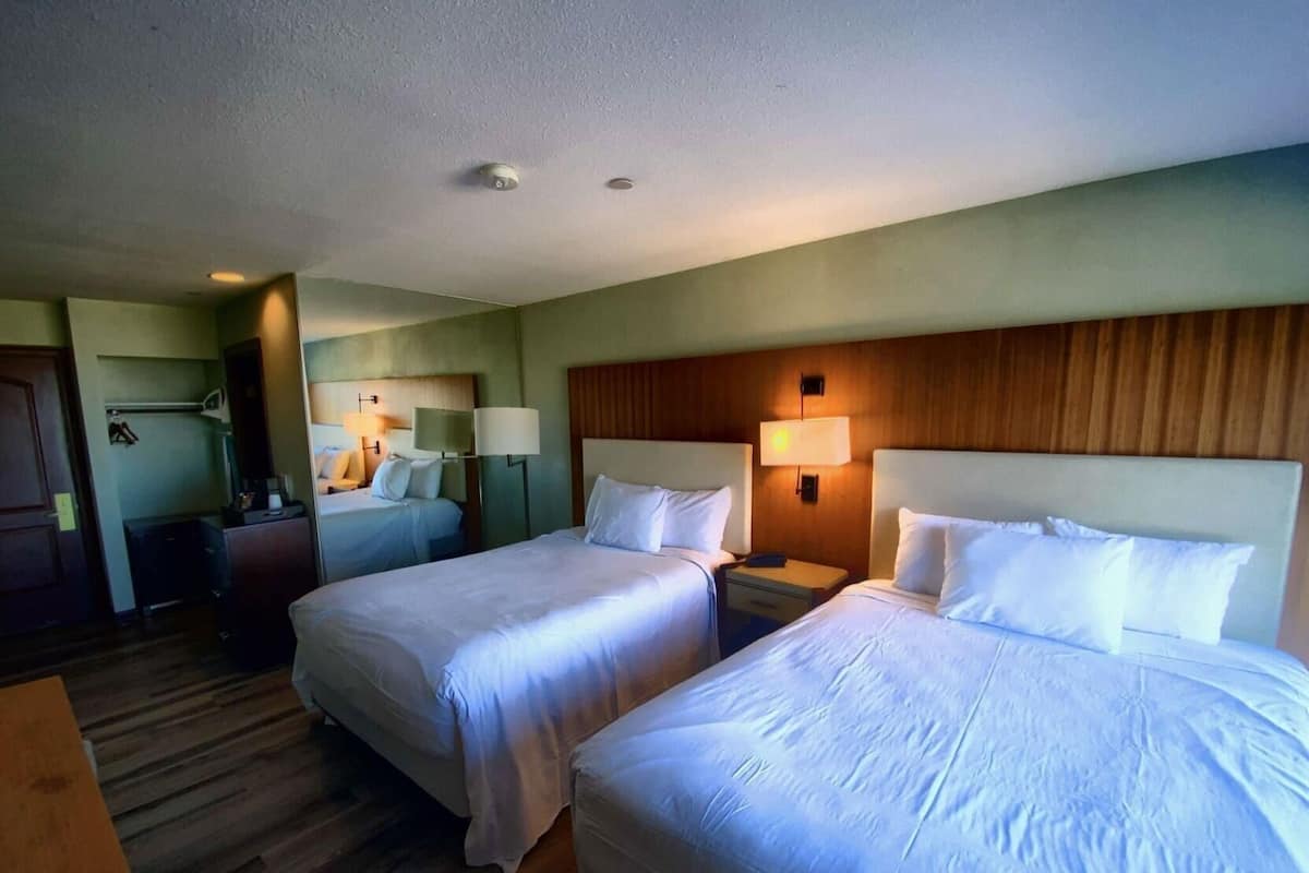 Una habitación de hotel con dos camas, un escritorio, una silla y una mesita.