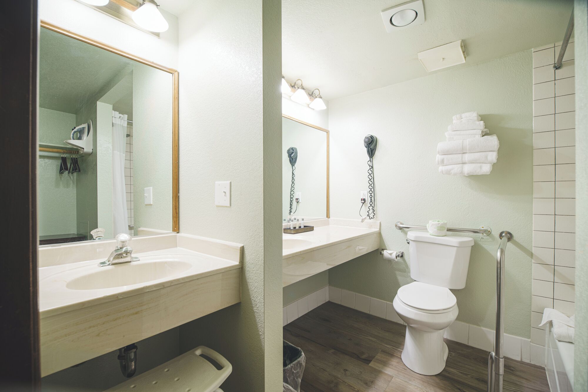 A bathroom with a sink, mirror, toilet, and a shower area.