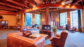 A spacious lobby with leather furniture, a stone fireplace, and large windows offering a view of the outdoors.