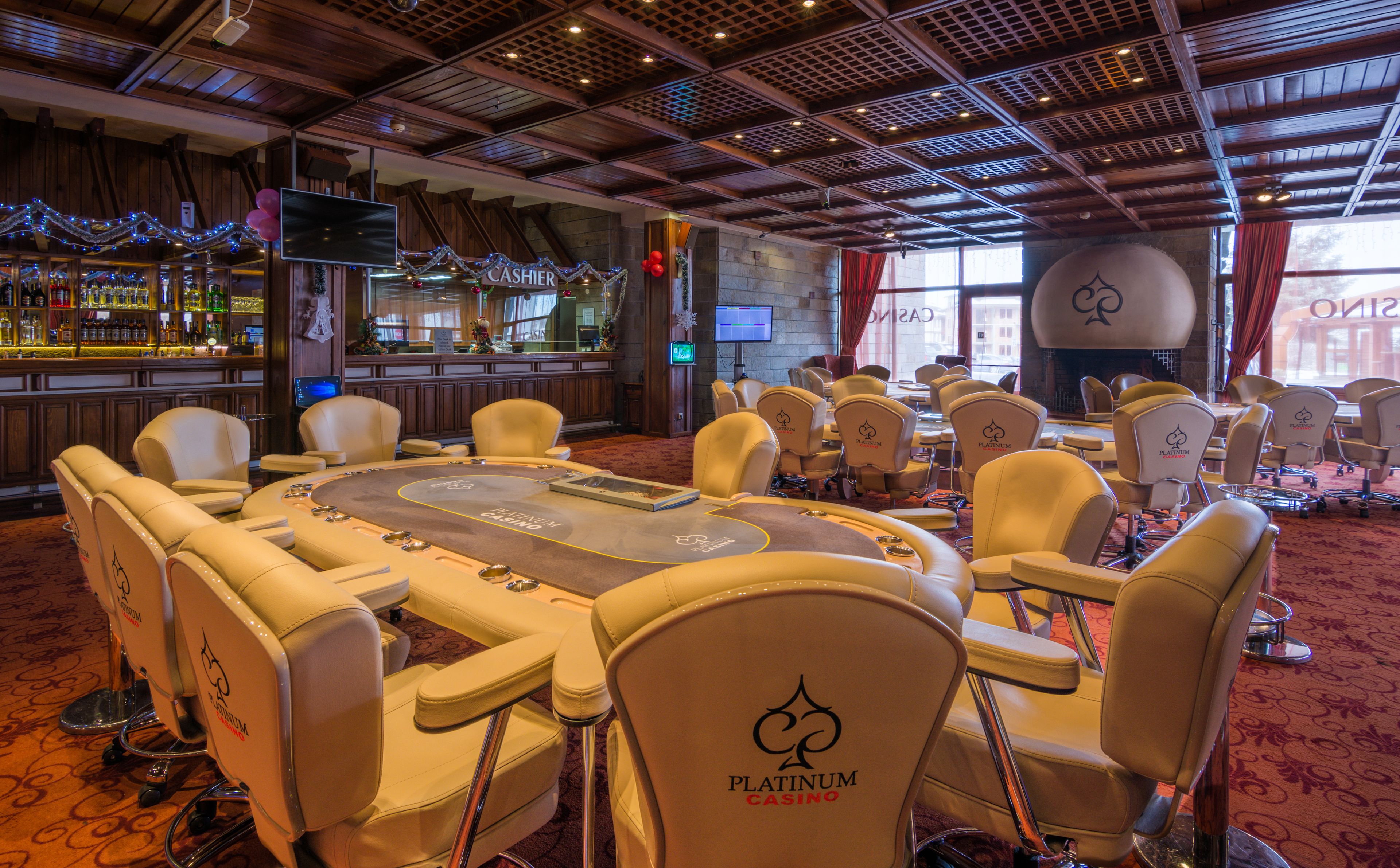 A casino with a large oval table, multiple gaming tables, and a bar area.