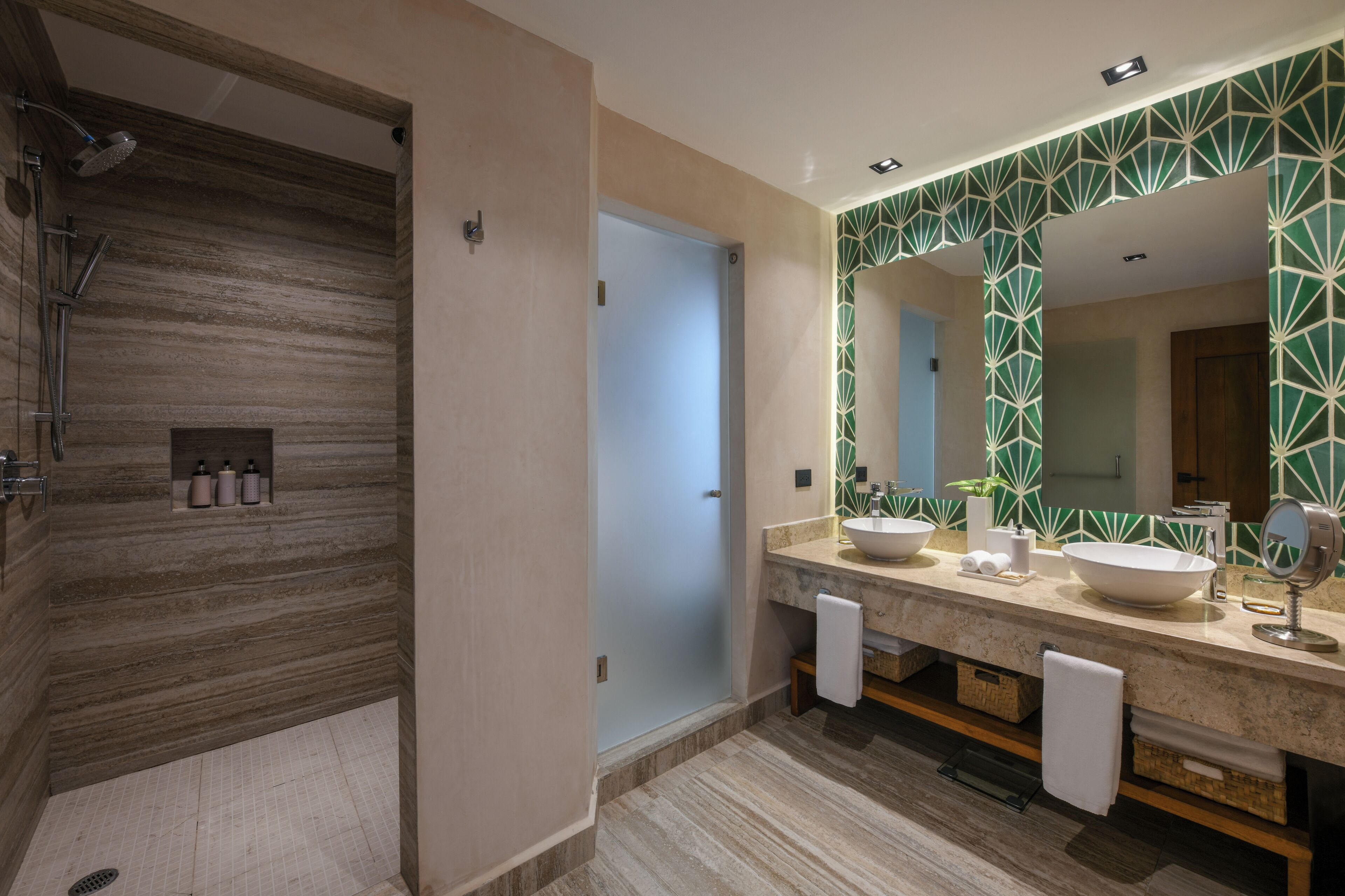 A modern bathroom with a walk-in shower, dual sinks, and a large mirror.