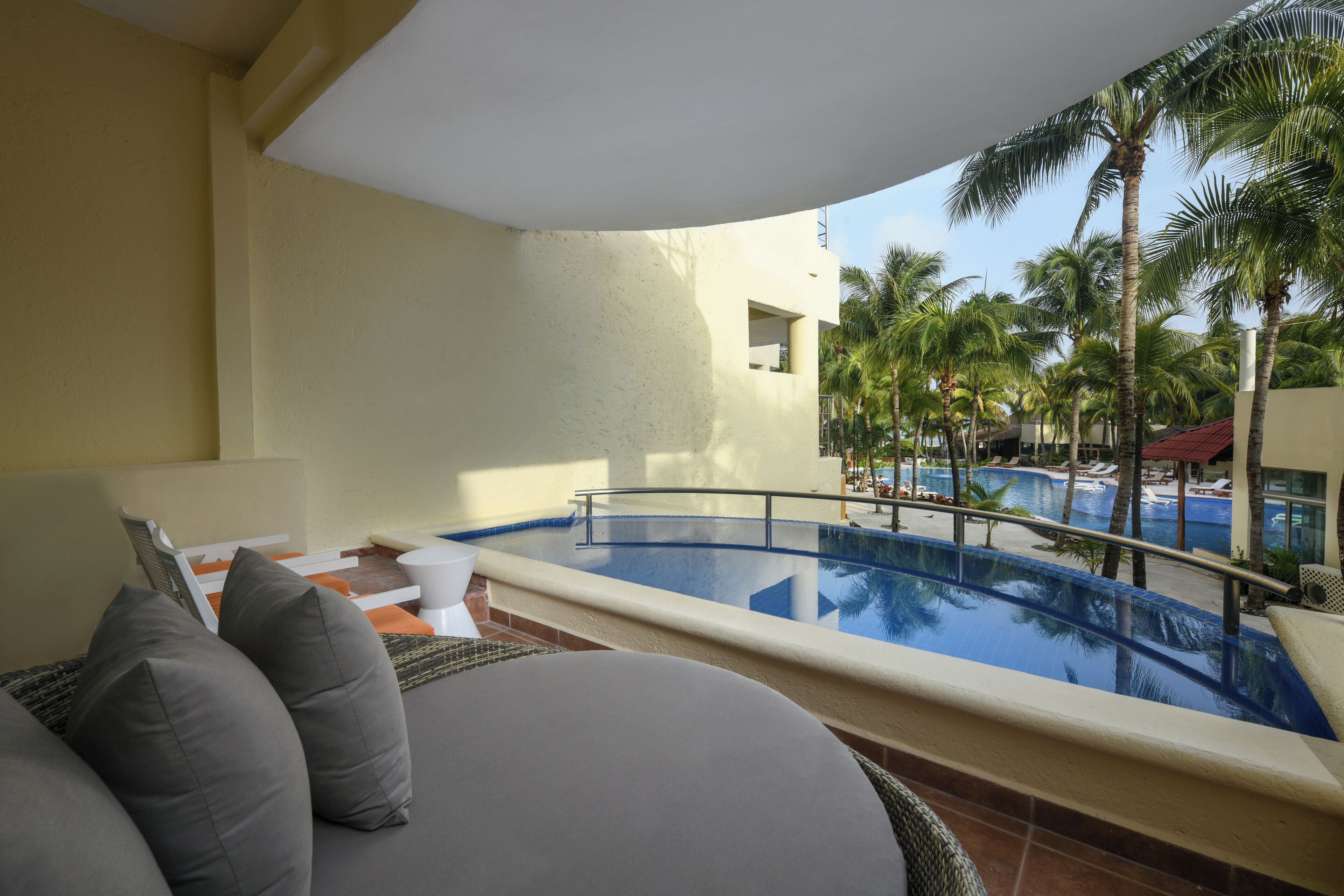 Un balcón con vistas a una piscina y palmeras.